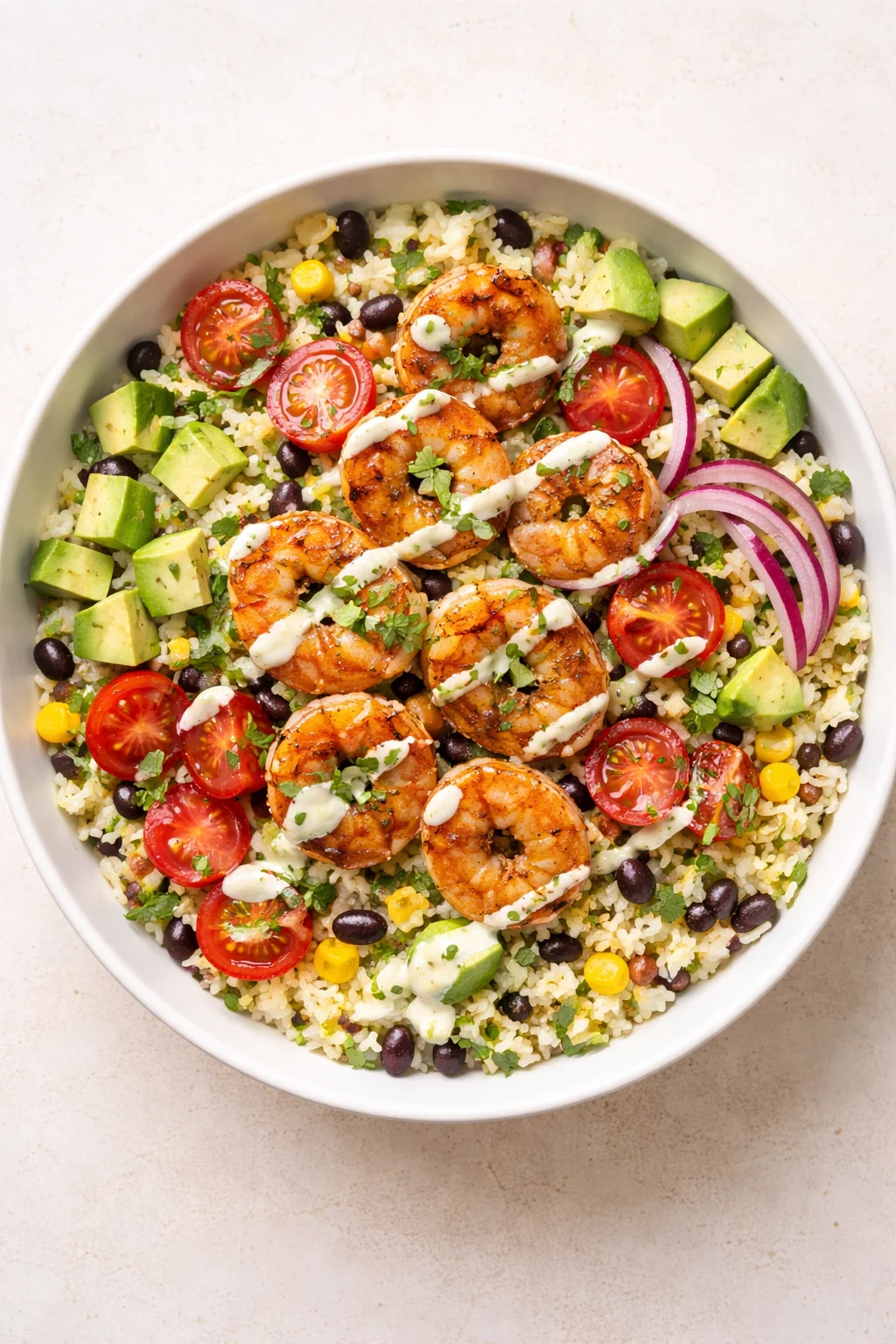 bowl of rice topped with grilled shrimp, avocado, cherry tomatoes, corn, black beans, and red onion