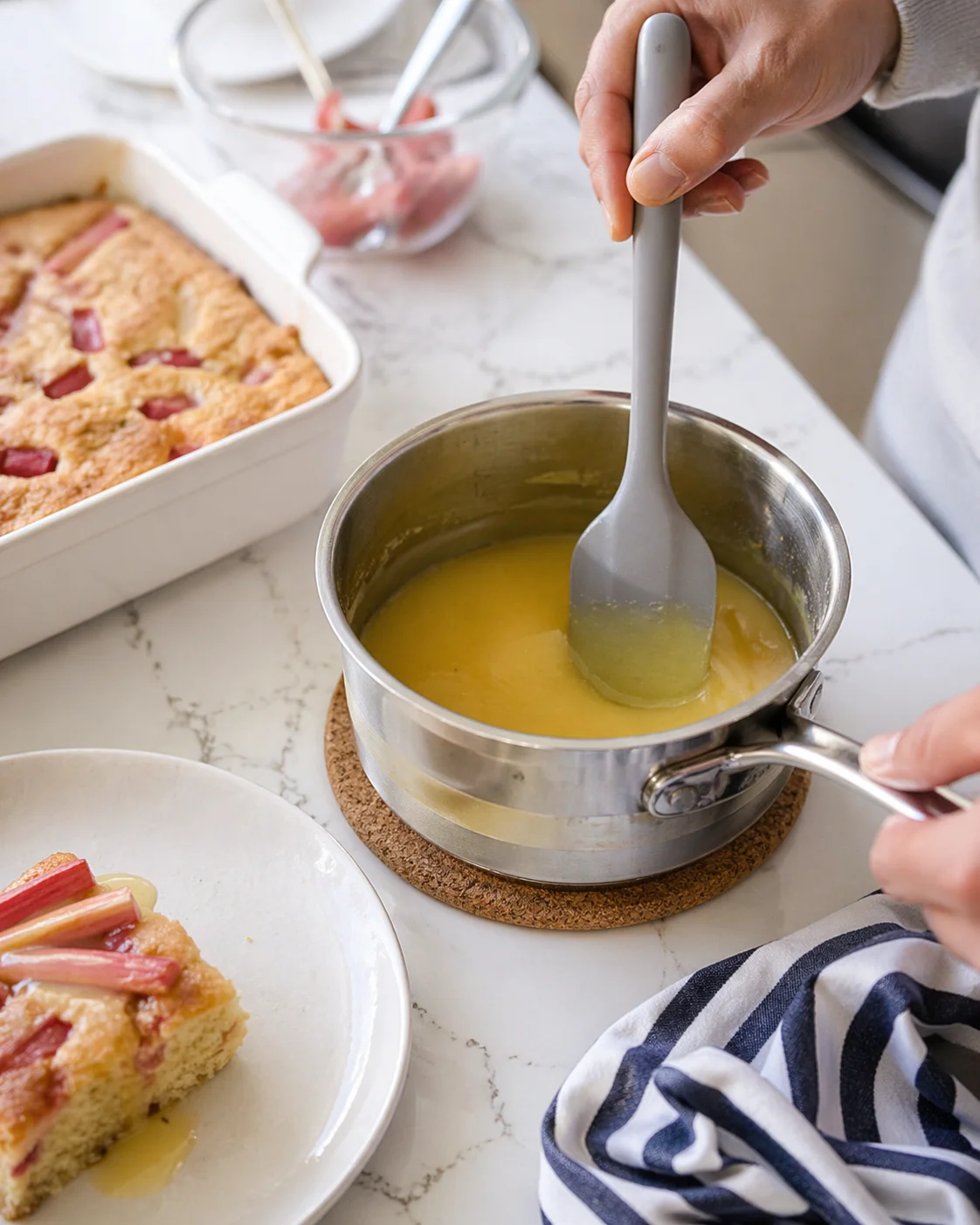Warm sauce being gently reheated in a small saucepan before drizzling over cake slices.