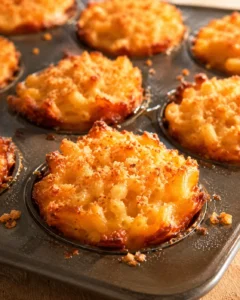 Close-up of golden brown apple crumble muffins in a dark muffin pan, rustic and inviting.