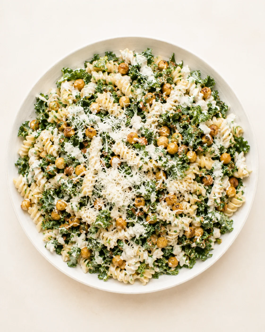 Creamy kale and chickpea pasta with parmesan in a white bowl.