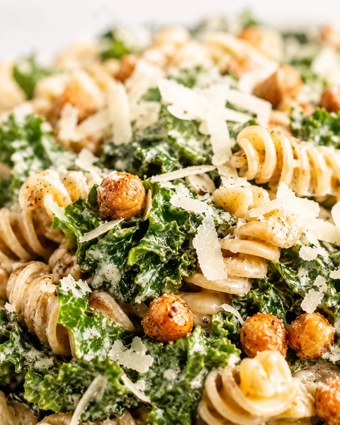 Close-up of creamy kale pasta with shaved parmesan and roasted chickpeas.