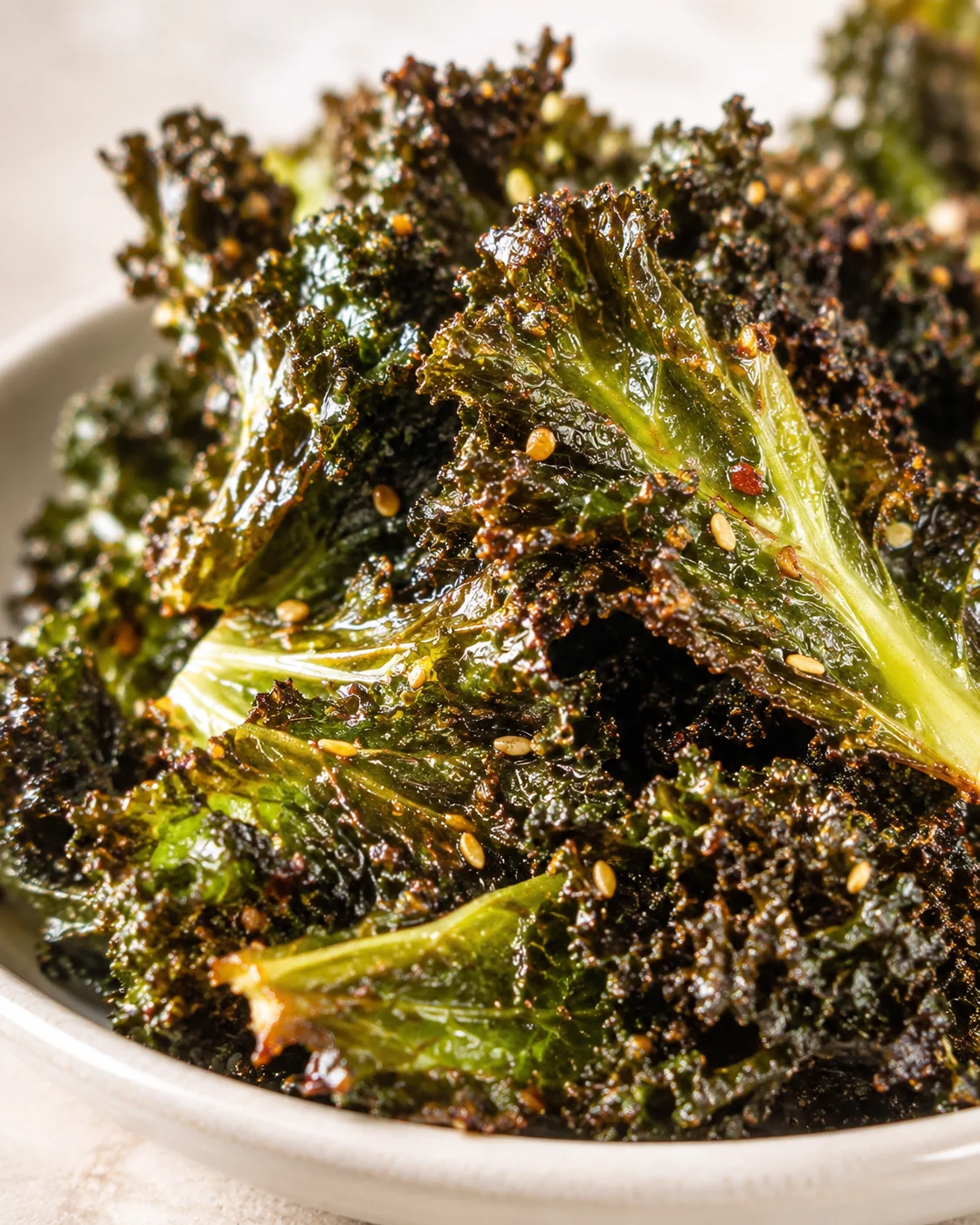 close-up of crispy kale chips with sesame seeds in a white bowl