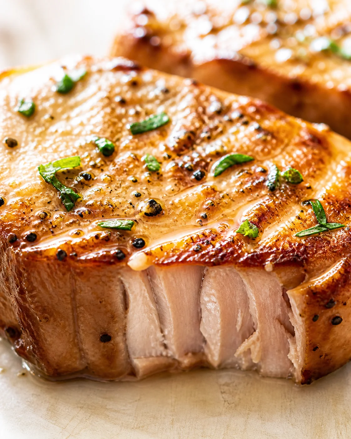close-up of roasted pork loin with crackling, herbs, and juicy interior.