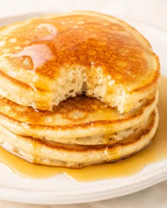 close-up of fluffy stacked pancakes with syrup on a plate