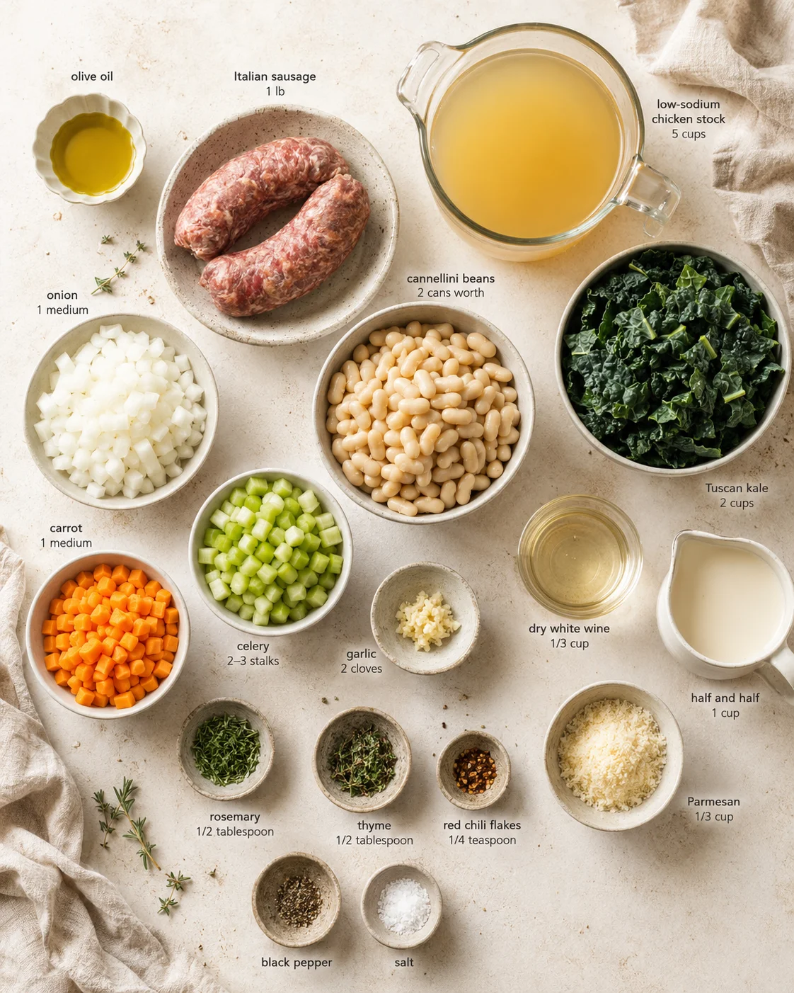 Overhead view of labeled recipe ingredients including sausage, kale, beans, and vegetables on a light counter.