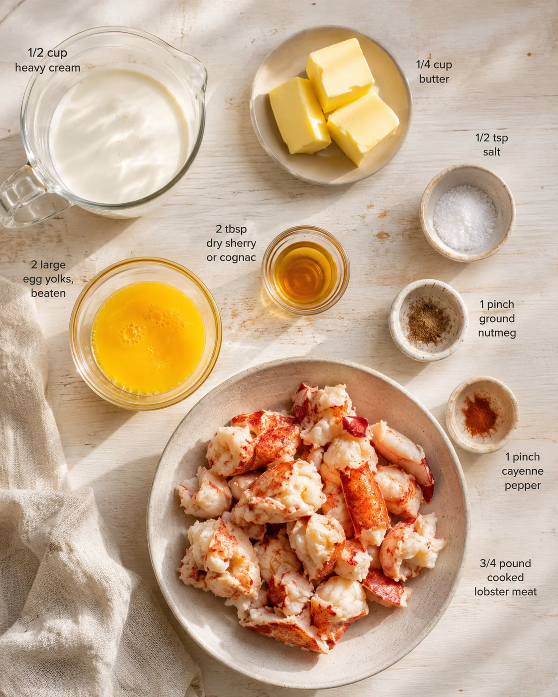 Overhead shot of lobster ingredients: cream, eggs, butter, lobster meat, spices, and liquor.