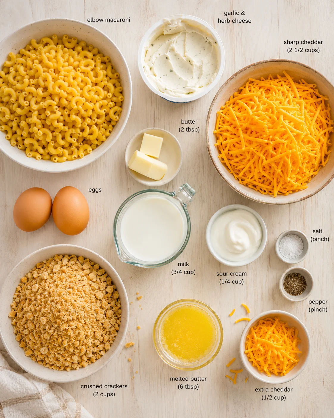 Overhead view of labeled macaroni and cheese ingredients laid out on a light wood surface.