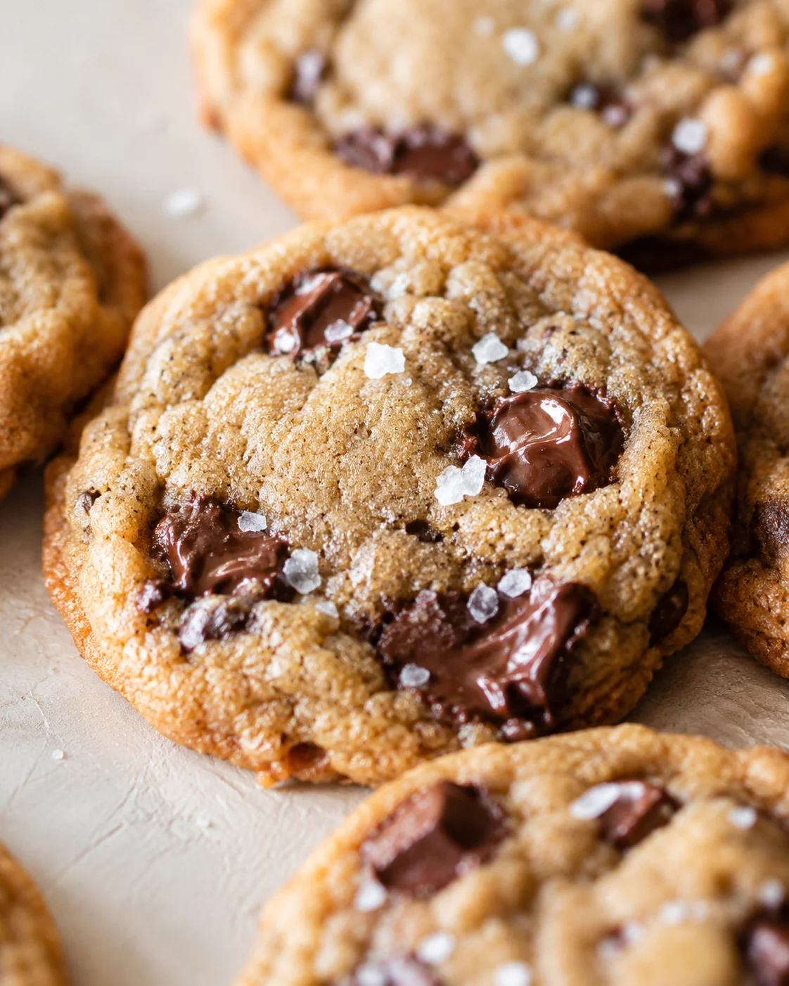 Close-up of golden-brown salted chocolate chunk cookies with melted chocolate and flaky salt.