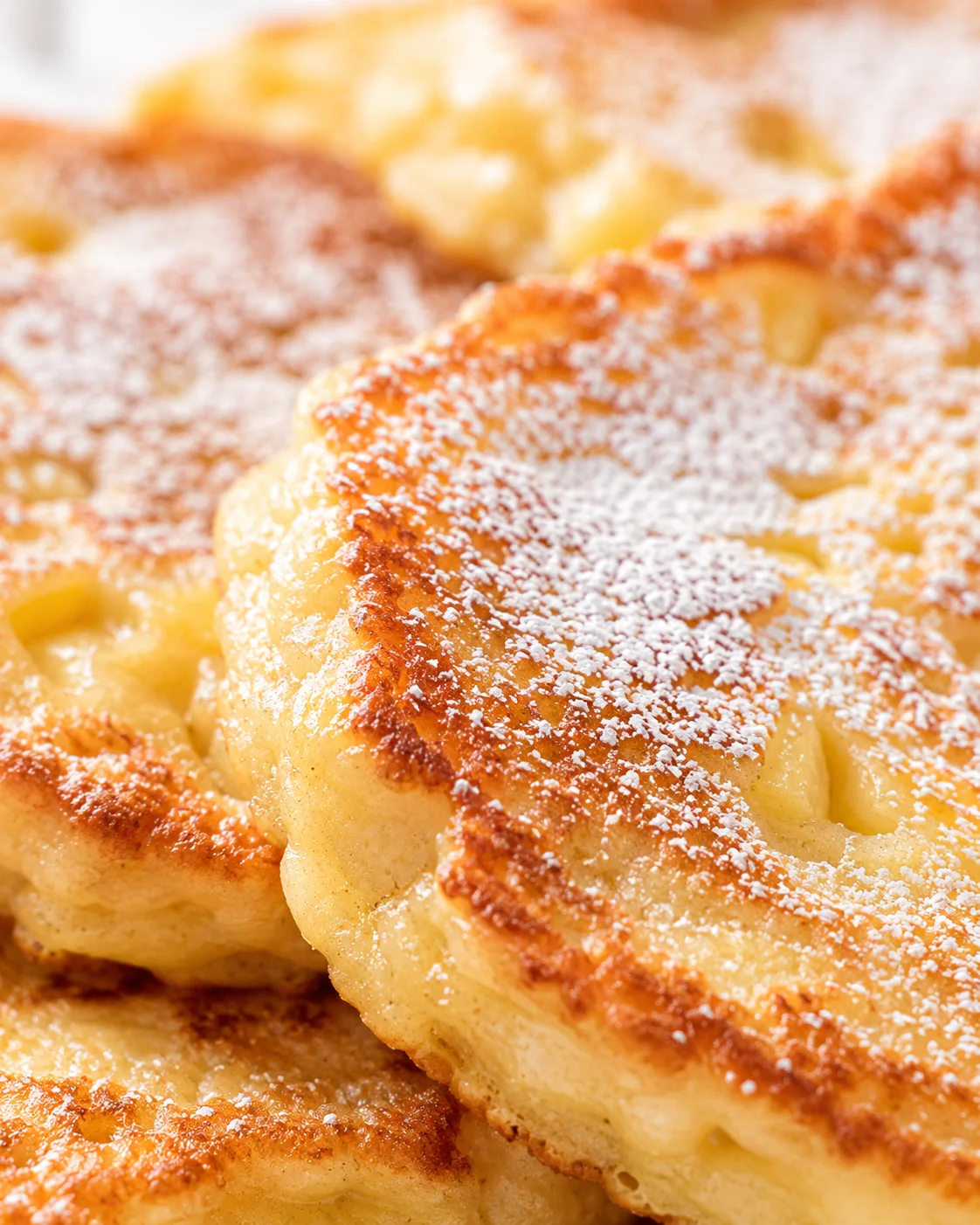 Close-up of golden-brown Danish pastries with flaky, buttery layers and powdered sugar