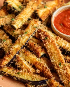 Golden, crispy eggplant fries with a side of marinara sauce in a bowl.