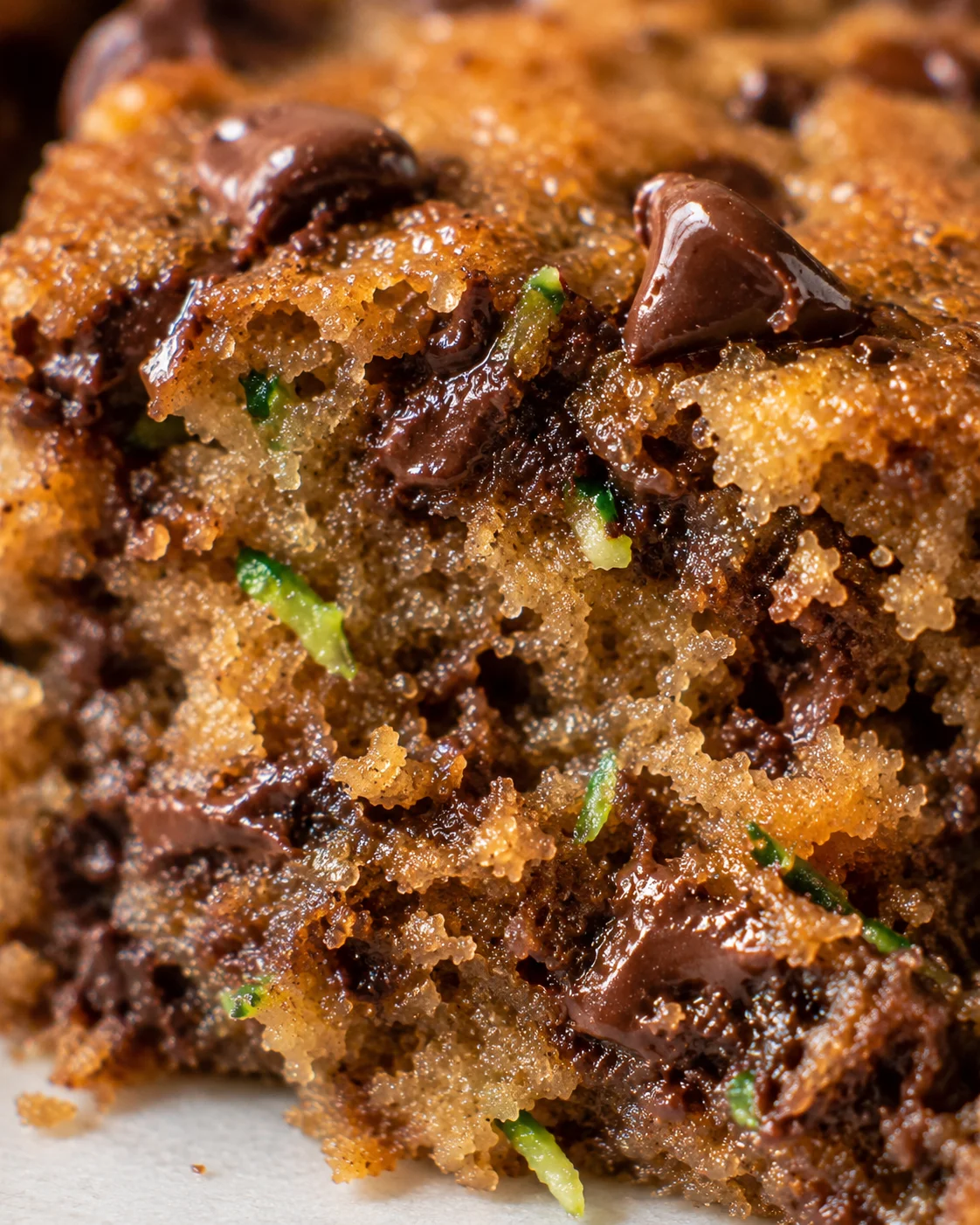 Close-up of moist, chewy chocolate zucchini bars with melted chocolate chips inside.