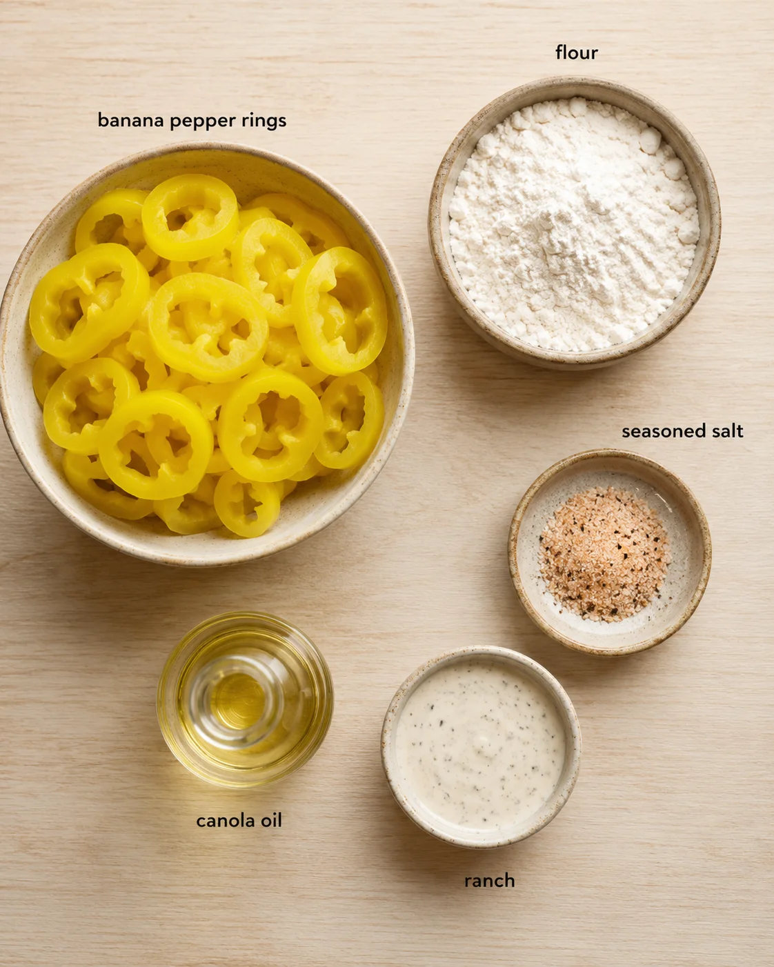 Bowl of sliced yellow banana peppers with flour, salt, ranch, and canola oil nearby