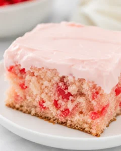 Close-up of a moist cherry vanilla cake with pink frosting and cherries inside.