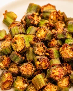 Baked okra pieces with a smoky, crispy texture and golden edges on a white plate