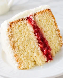 Close-up of a slice of vanilla cake with strawberry filling and cream cheese frosting