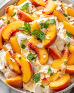 Colorful peaches, whipped cream, mint, and almonds in a fresh salad.