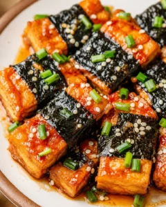 Close-up of flavorful seaweed tofu rolls topped with green onions and sesame seeds.