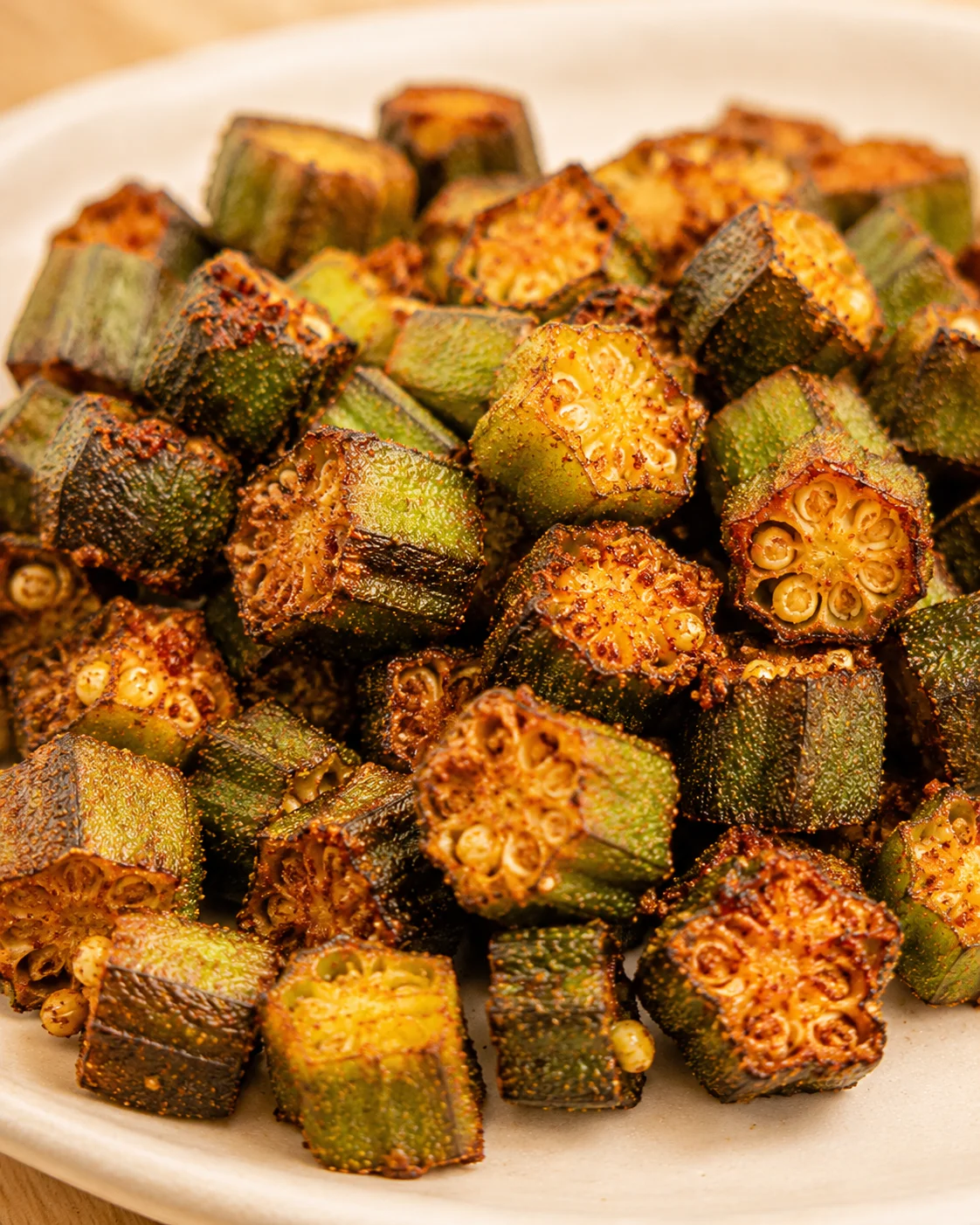 Crispy, smoky roasted okra pieces on a white plate, perfect for a flavorful side.