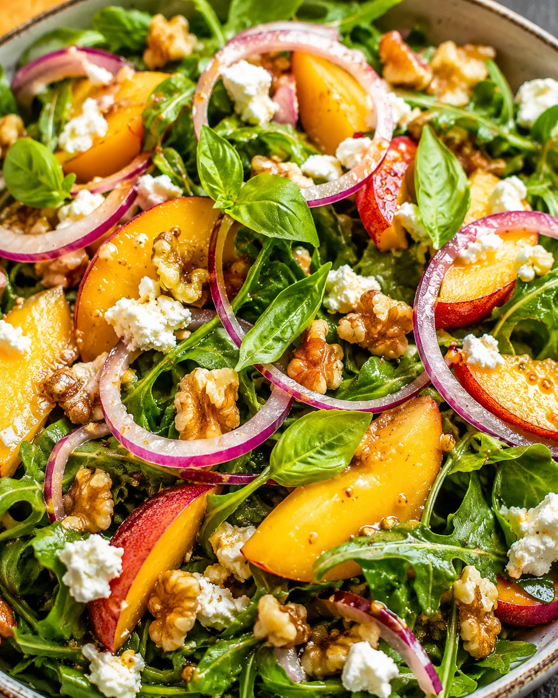 Mediterranean Peach Salad Colorful peach salad with greens, red onions, walnuts, and feta cheese.