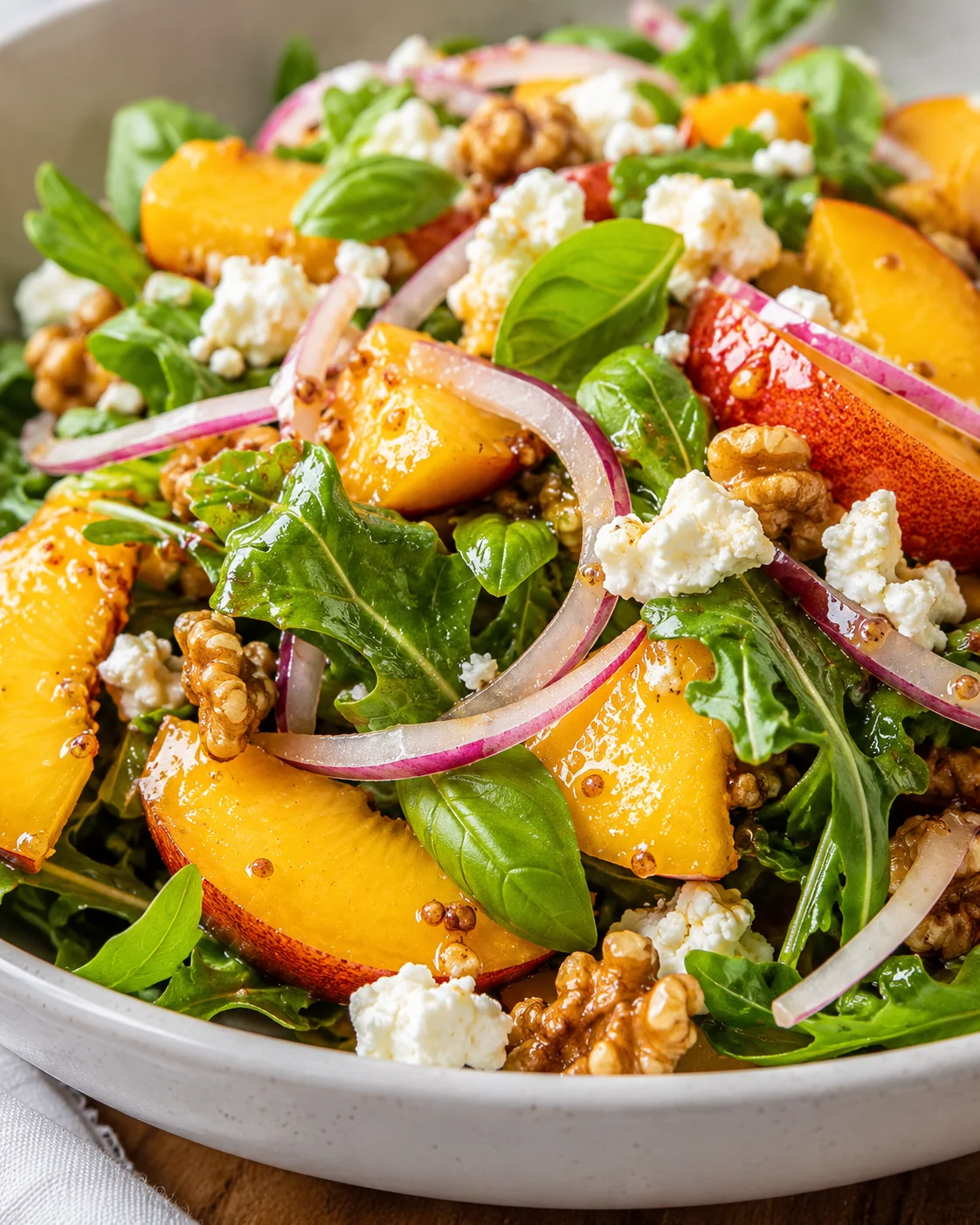 Mediterranean Peach Salad Colorful peach salad with goat cheese, basil, arugula, walnuts, and red onions.