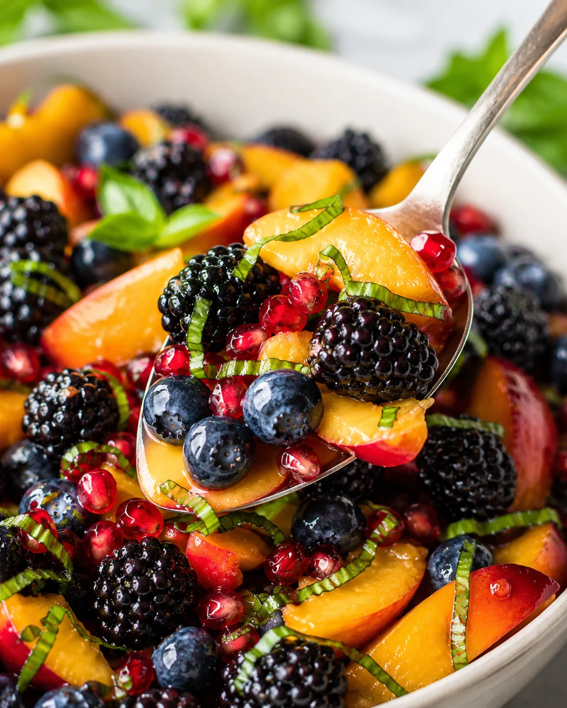 A vibrant mix of fresh peaches, blackberries, blueberries, and pomegranate seeds