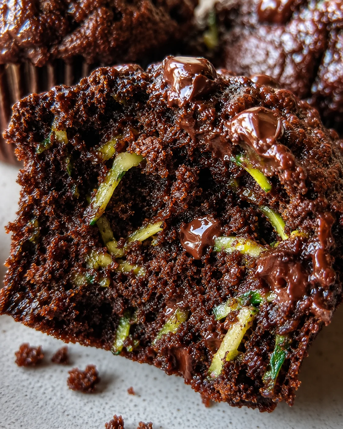 Close-up of moist chocolate zucchini muffin with chocolate chips.