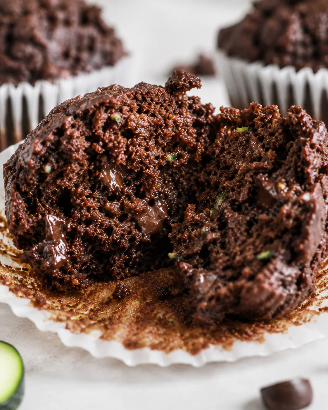 Healthy Moist Chocolate Zucchini Muffins Close-up of a muffin with a moist, chocolatey inside and shredded zucchini bits.
