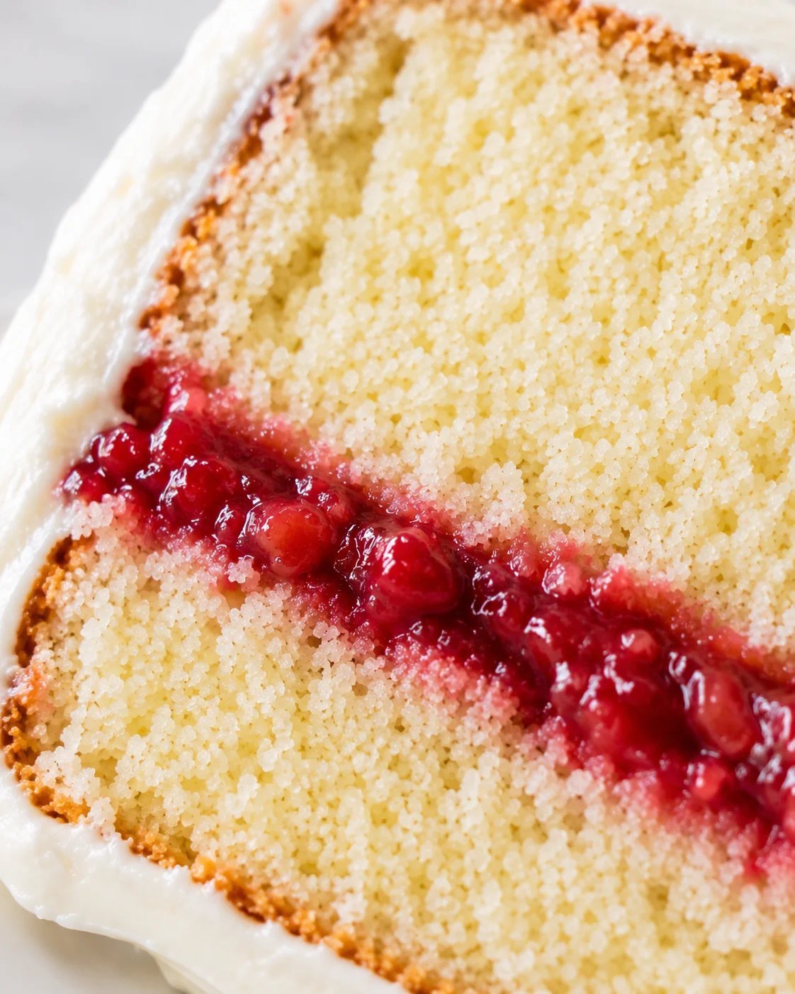 Close-up of a layered vanilla cake with strawberry filling and cream cheese frosting touch