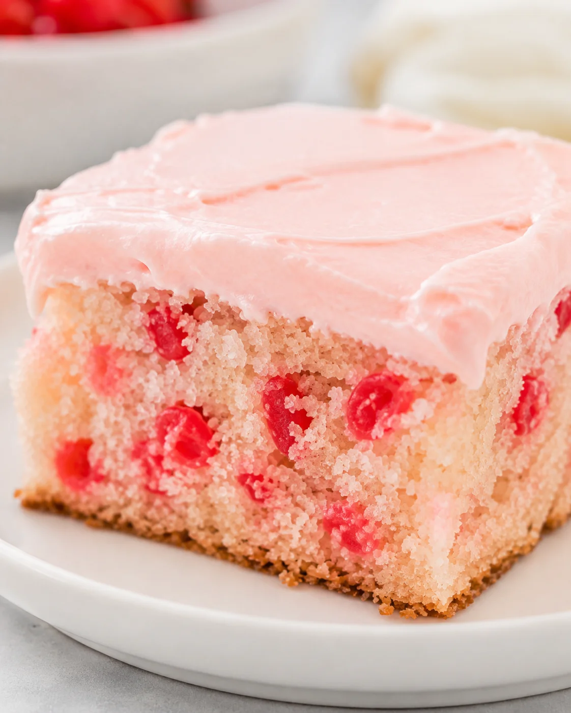 Moist cherry vanilla cake with pink frosting and cherry toppings