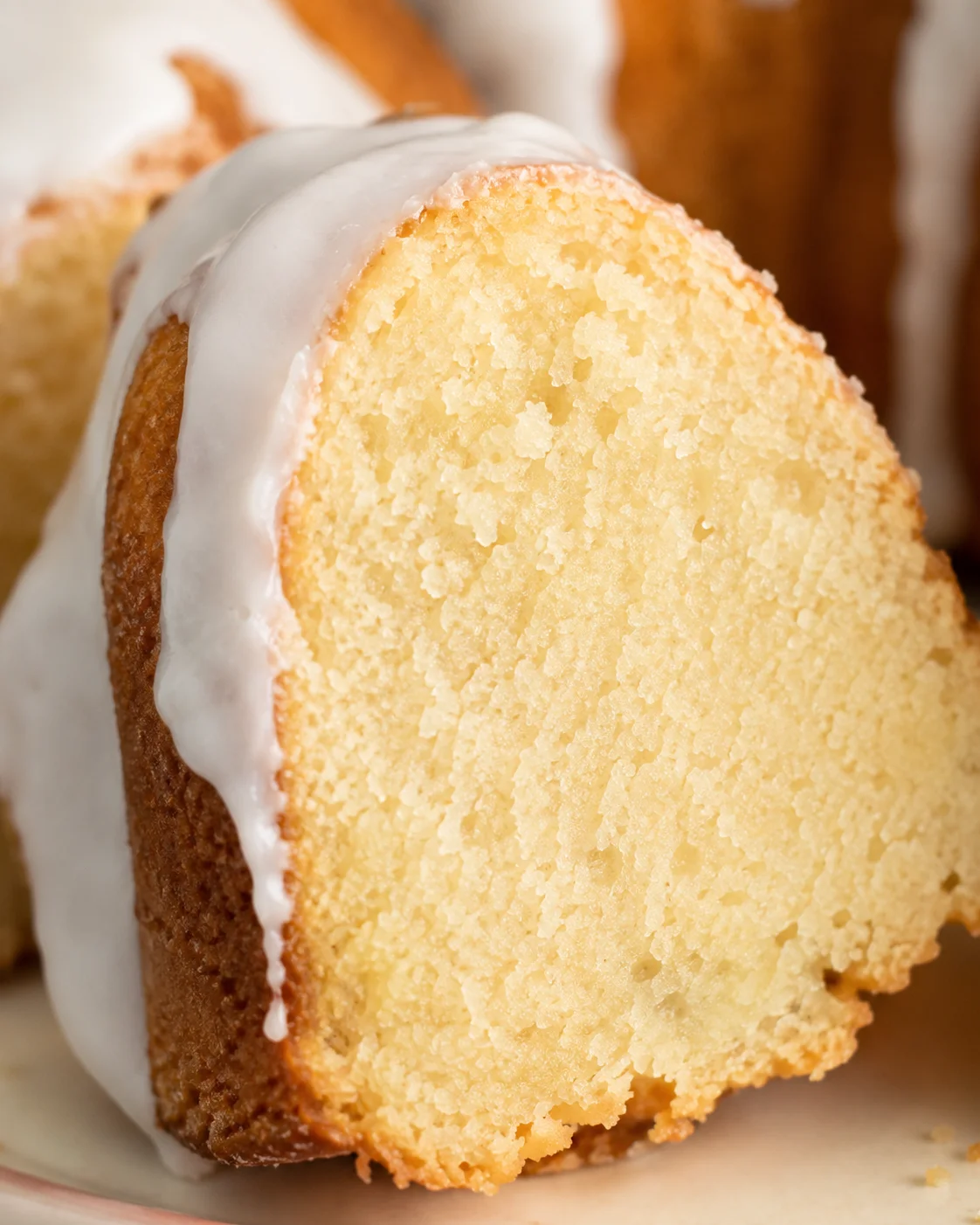 Close-up of moist vanilla bundt cake with smooth white glaze topping.