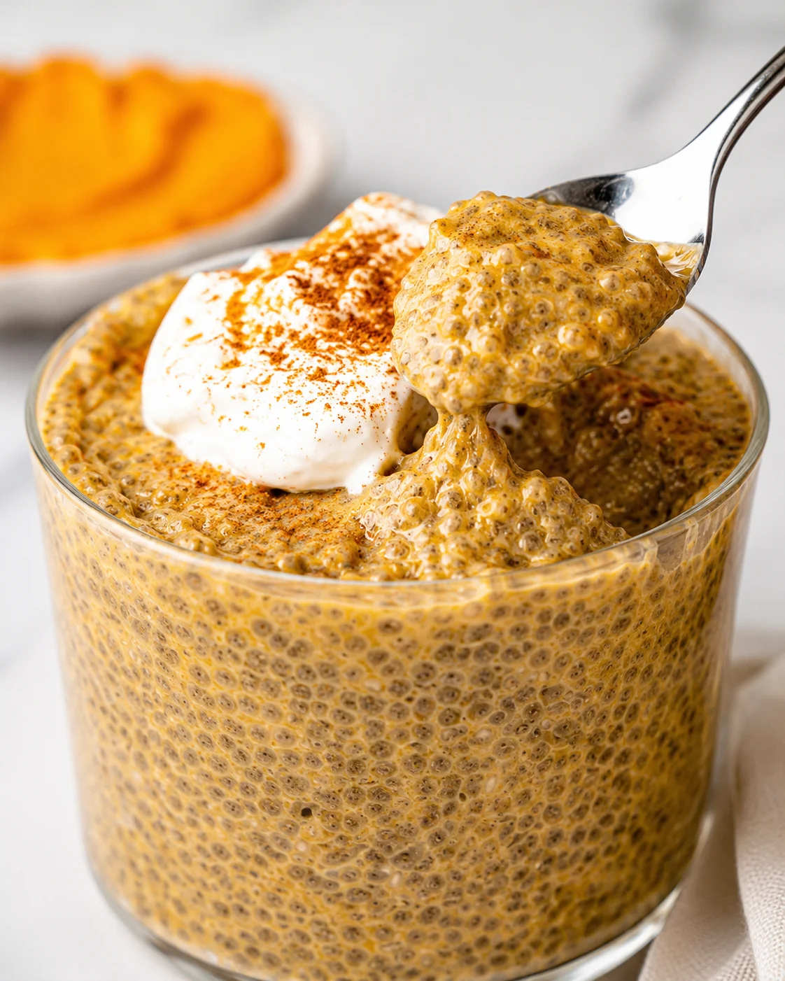 Delicious pumpkin chia pudding topped with whipped cream and spices, served in a glass.