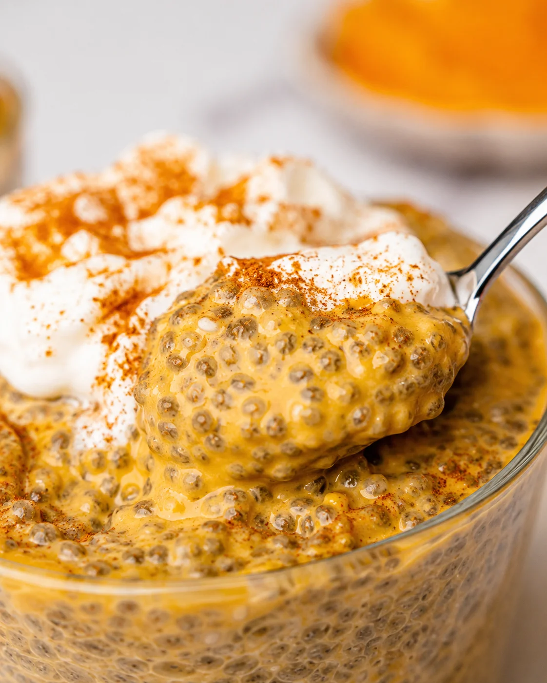 Creamy pumpkin chia pudding topped with whipped cream and a sprinkle of cinnamon.