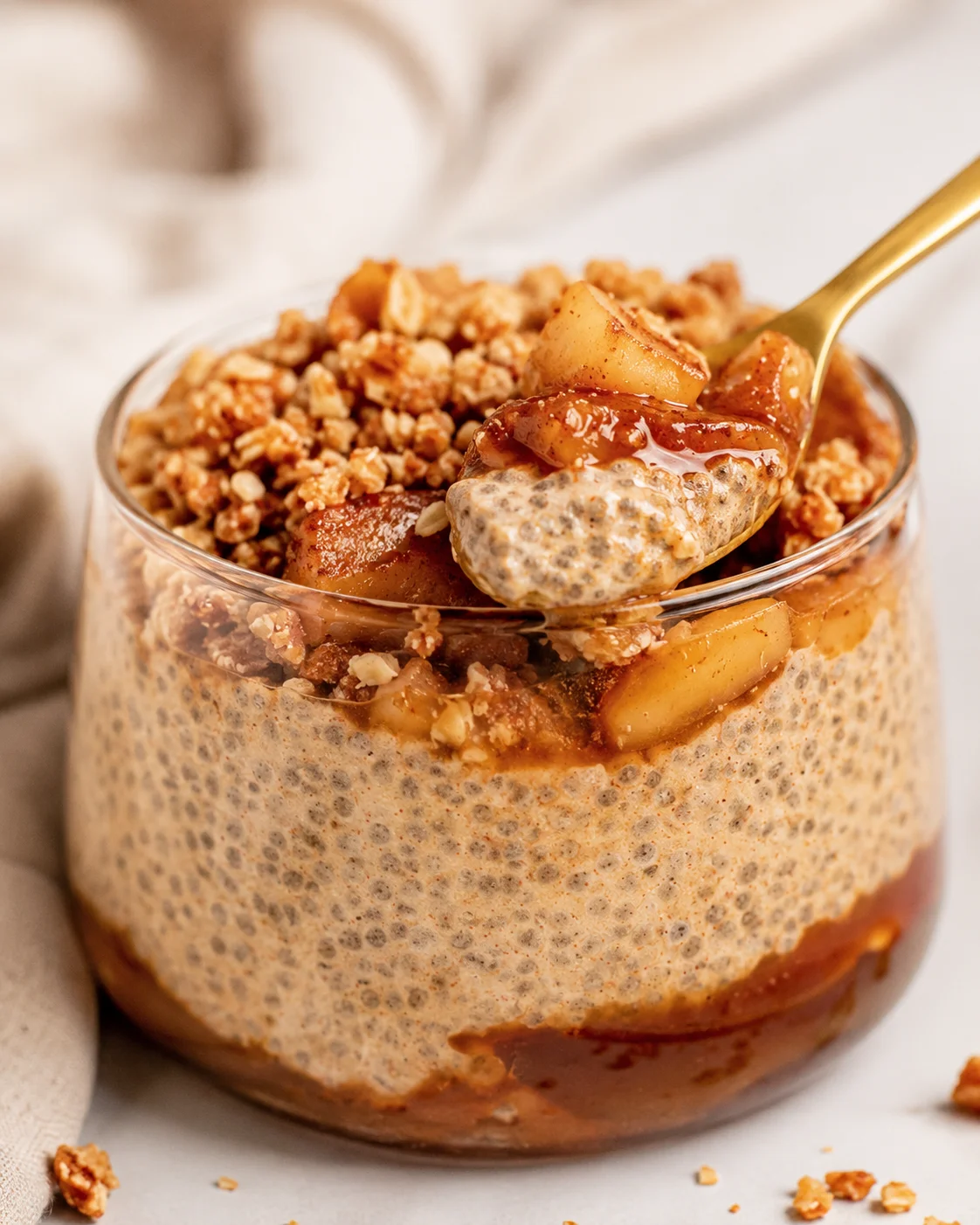 Creamy chia pudding topped with stewed apples and crunchy crumble in a glass