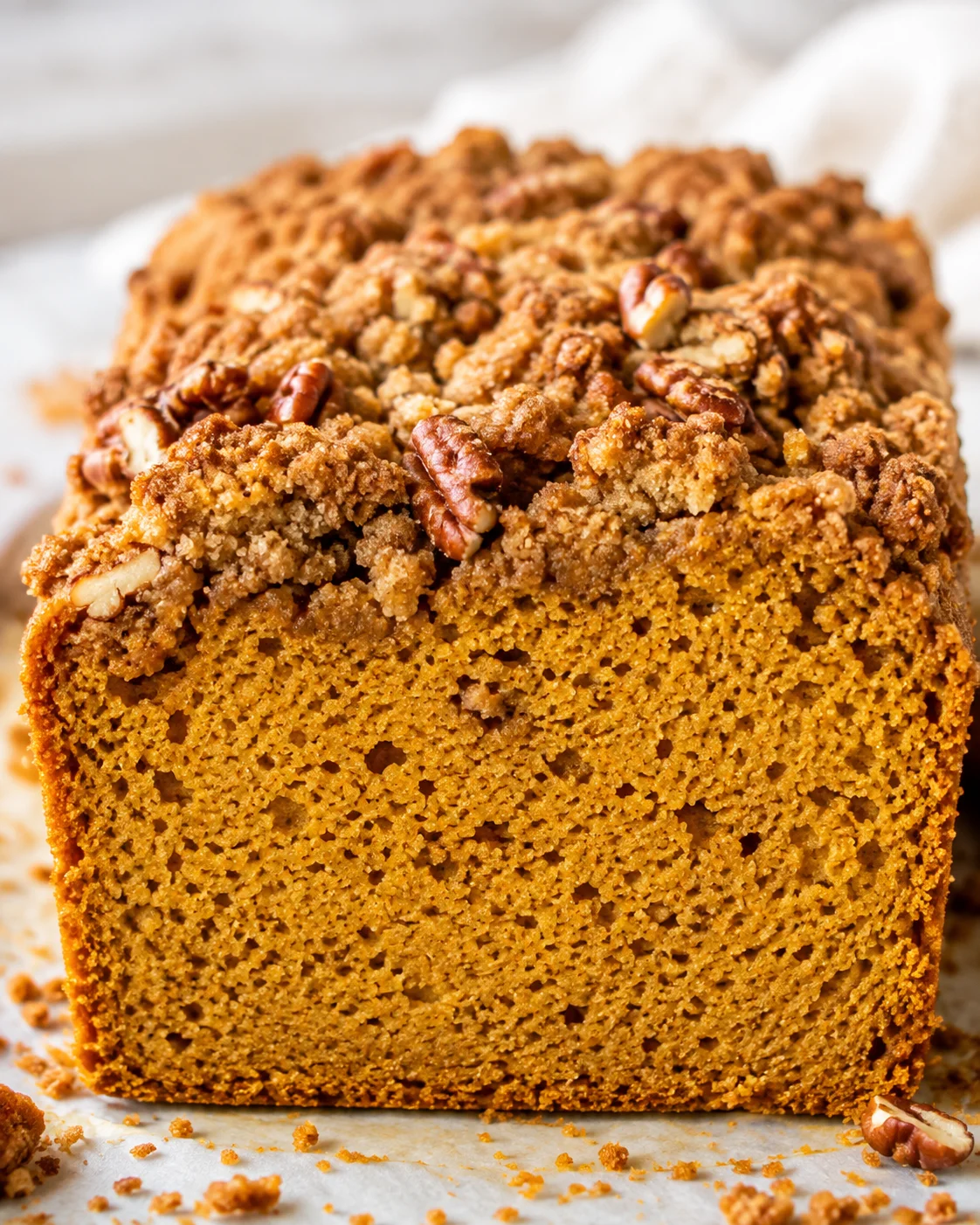 Front-facing loaf of almond flour pumpkin bread with pecan streusel topping showing interior crumb