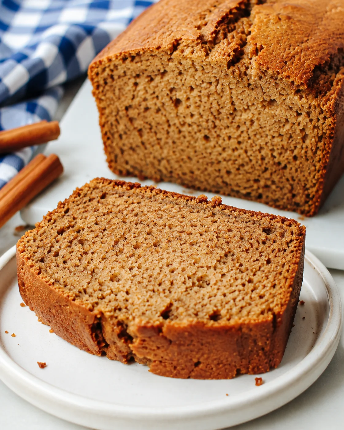 Cinnamon Applesauce Bread loaf with a sliced piece on a small plate