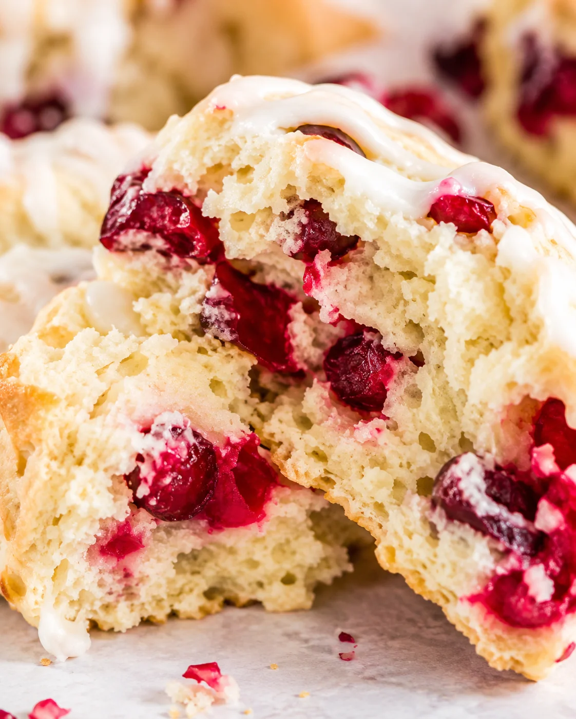 Close-up of a split cranberry scone showing crumb, berries, and glaze