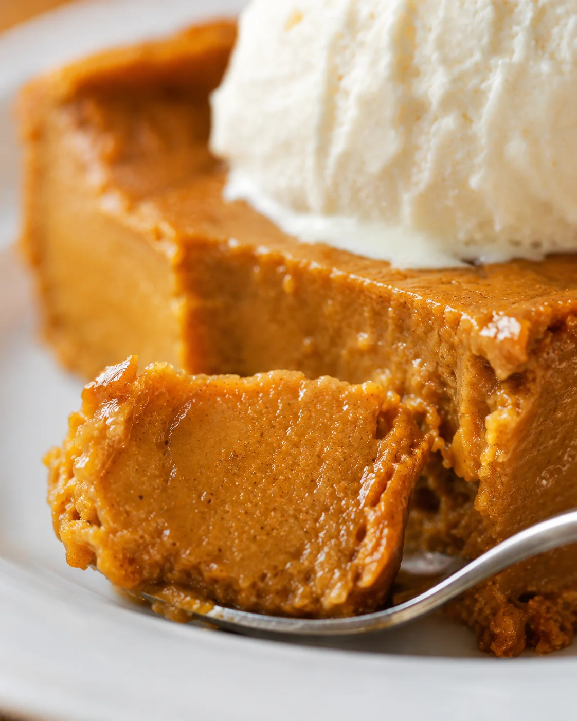 Close-up detail of crustless pumpkin pie interior with a spoonful and vanilla ice cream visible