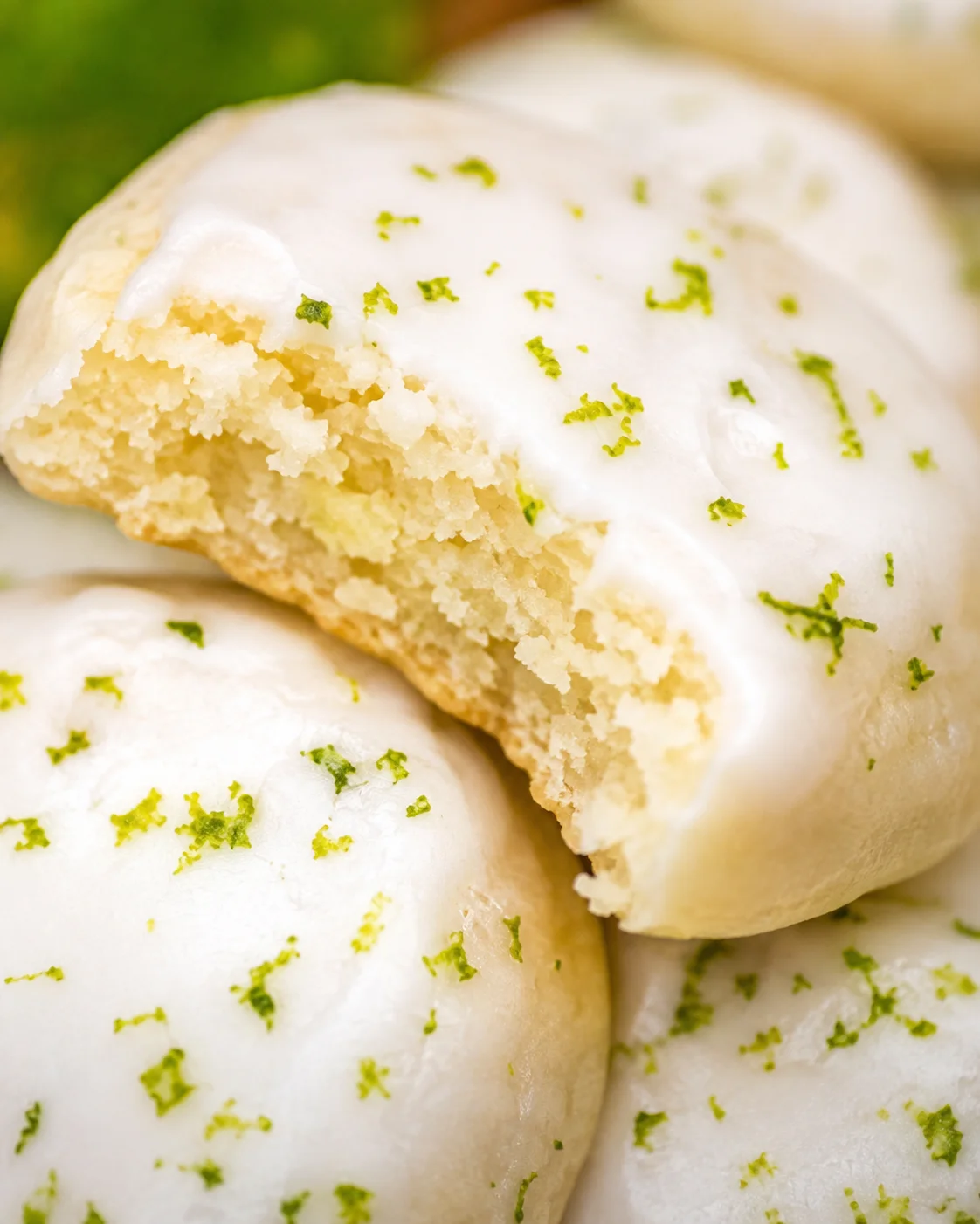 Macro close-up of a bitten key lime cookie showing crumb texture under lime-zested glaze