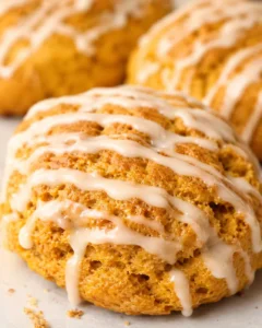 Close-up of a glazed maple pumpkin scone showing the golden crust and drizzle.