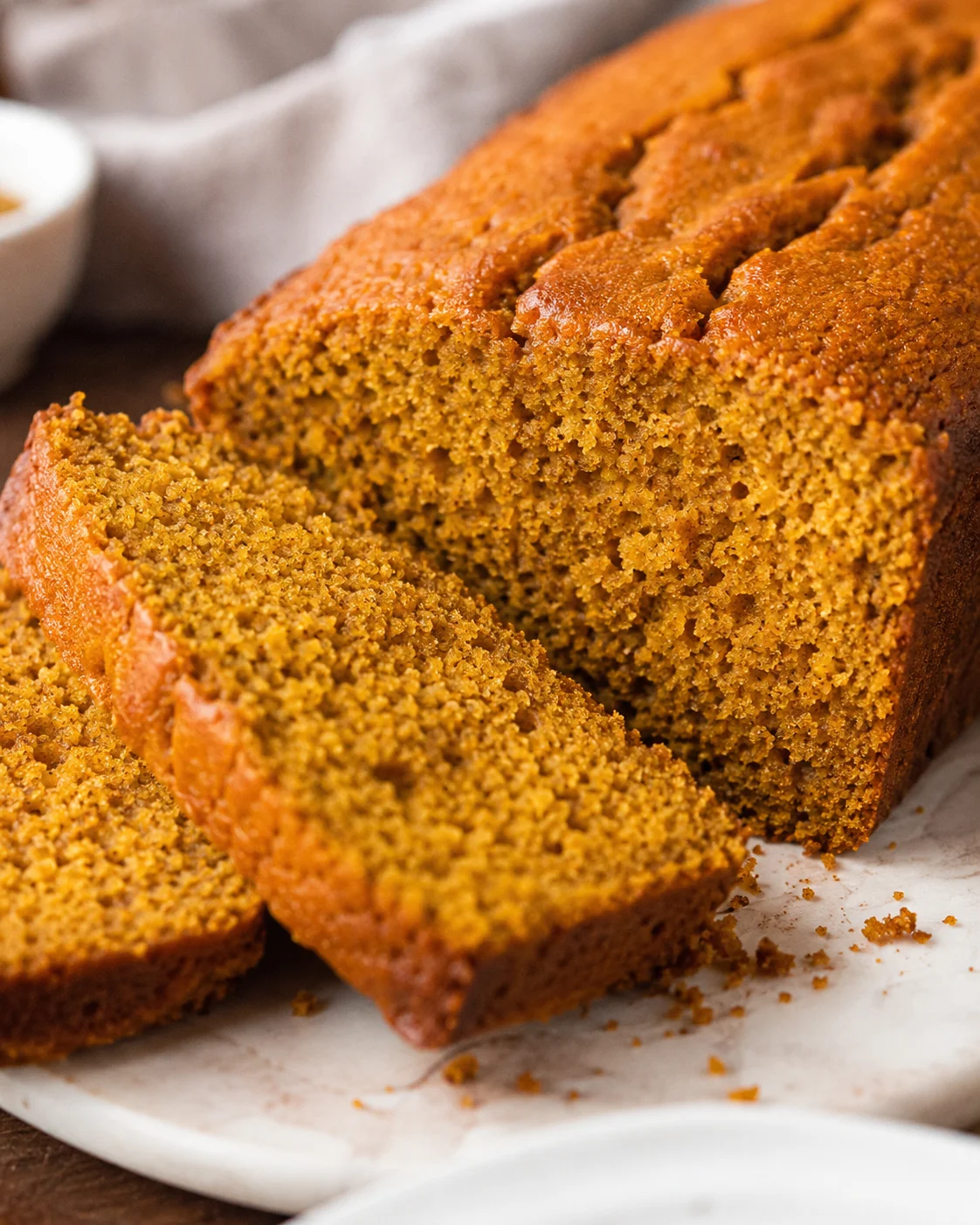 Sliced moist sour cream pumpkin bread loaf on a marble board