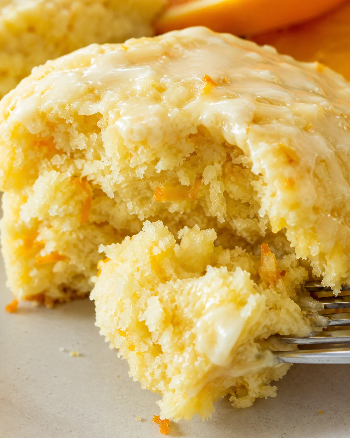 Fork pulling apart the interior crumb of a glazed orange scone
