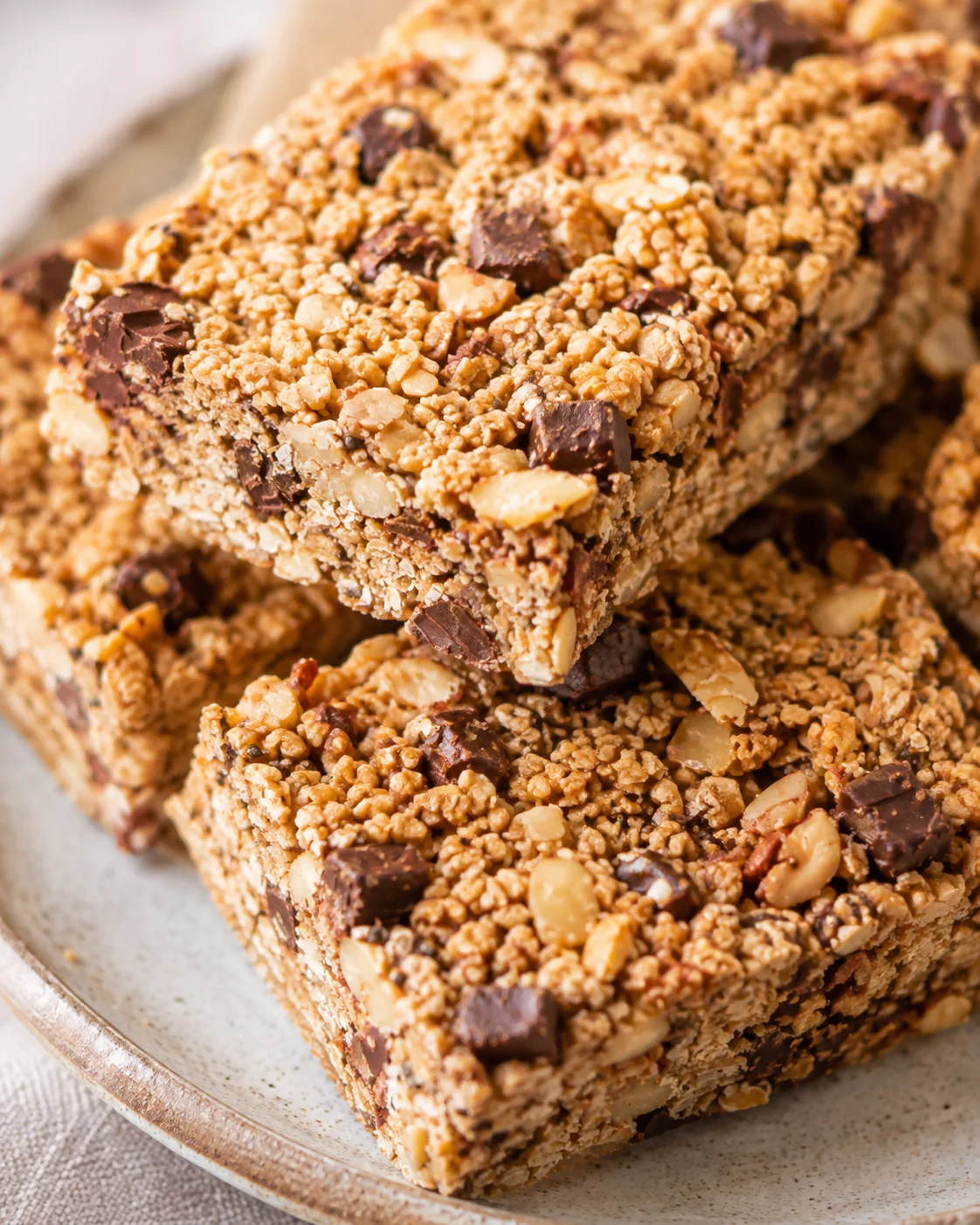 Homemade sourdough granola bars with nuts, chocolate, and dried fruit on a plate.
