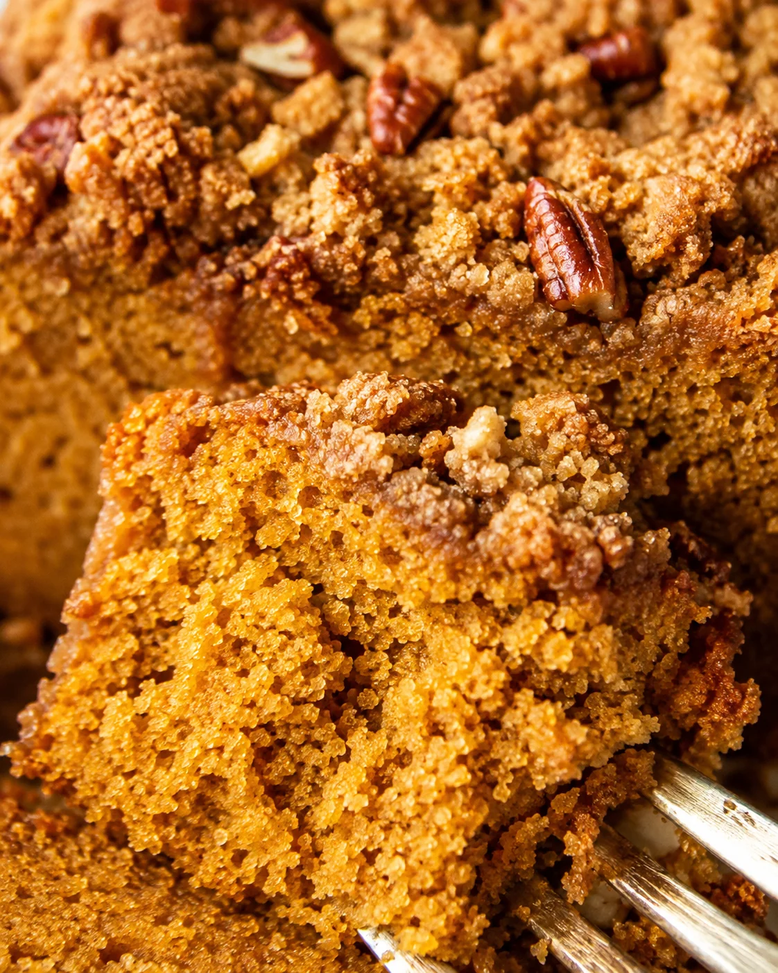 Close-up of a forkful of almond flour pumpkin bread showing moist crumb and streusel with pecans