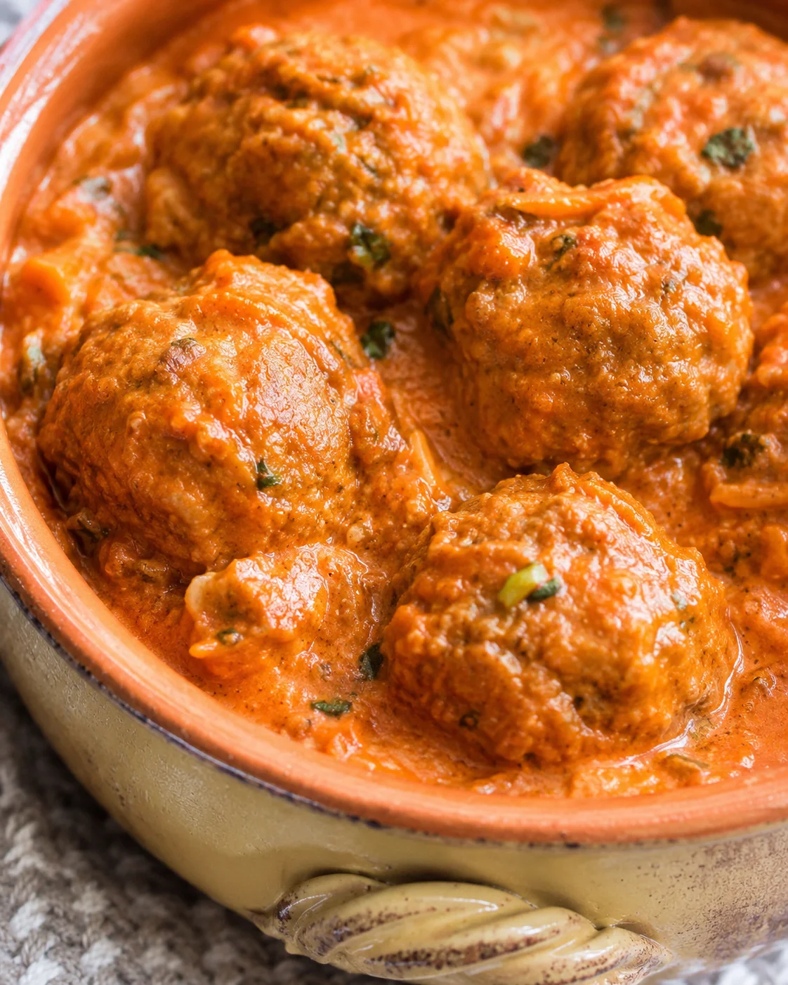 Pumpkin turkey meatballs simmering in creamy harvest tomato sauce in a rustic casserole