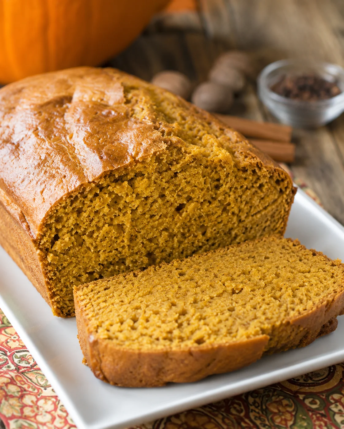 sliced sweetened condensed milk pumpkin bread on a white platter with one slice laid in front