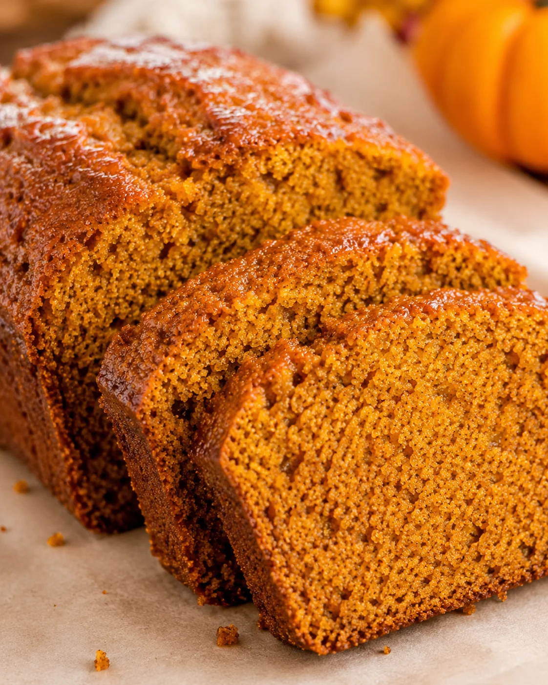 Sliced vegan pumpkin applesauce bread loaf with glossy crust and warm orange crumb