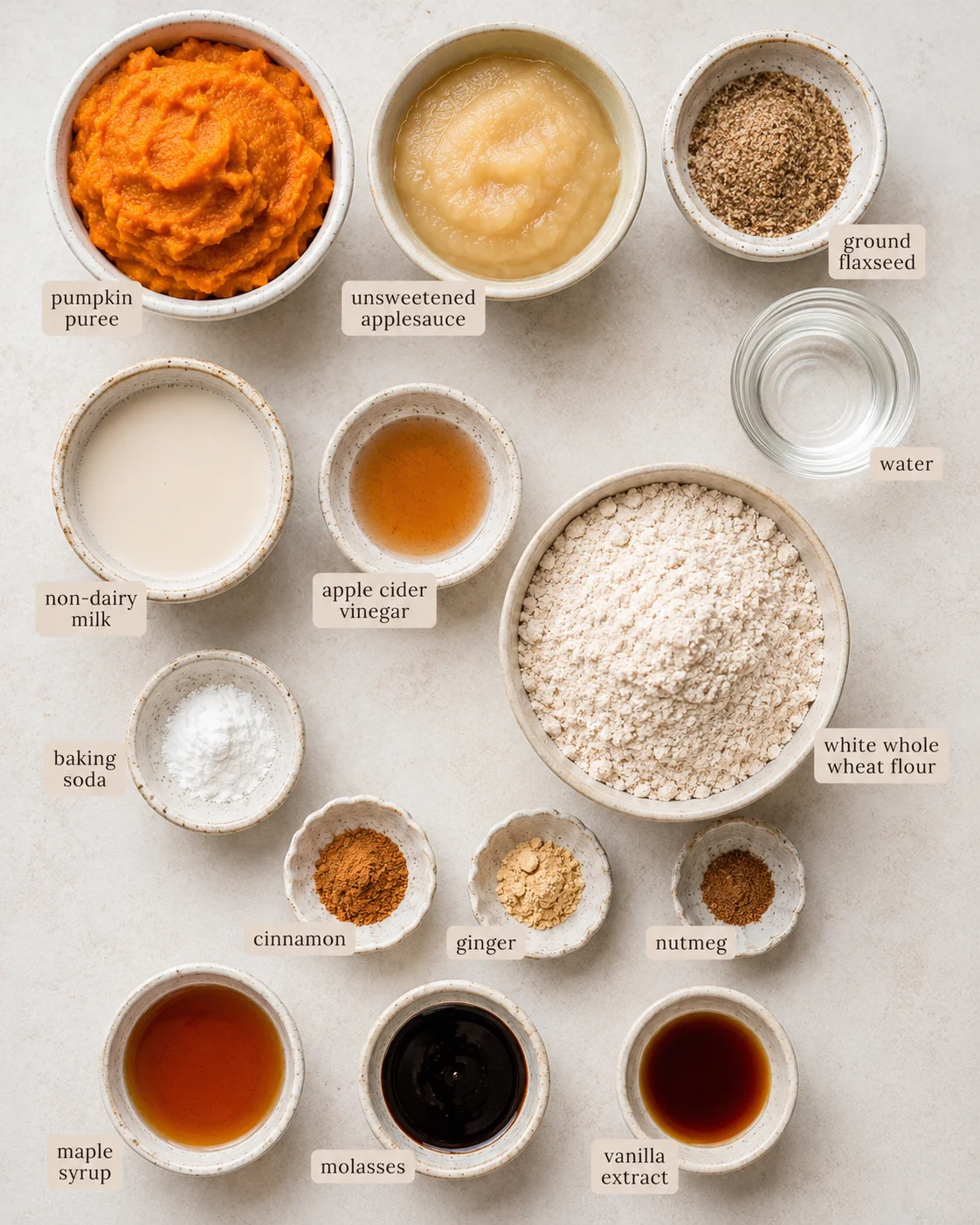 Top-down composition of bowls with pumpkin puree, applesauce, flour, spices and wet ingredients for vegan pumpkin applesauce bread
