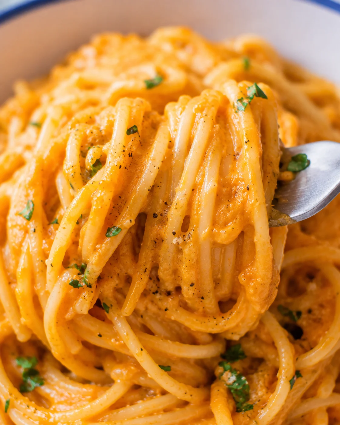Close-up detail of spaghetti strands coated in creamy pumpkin sauce
