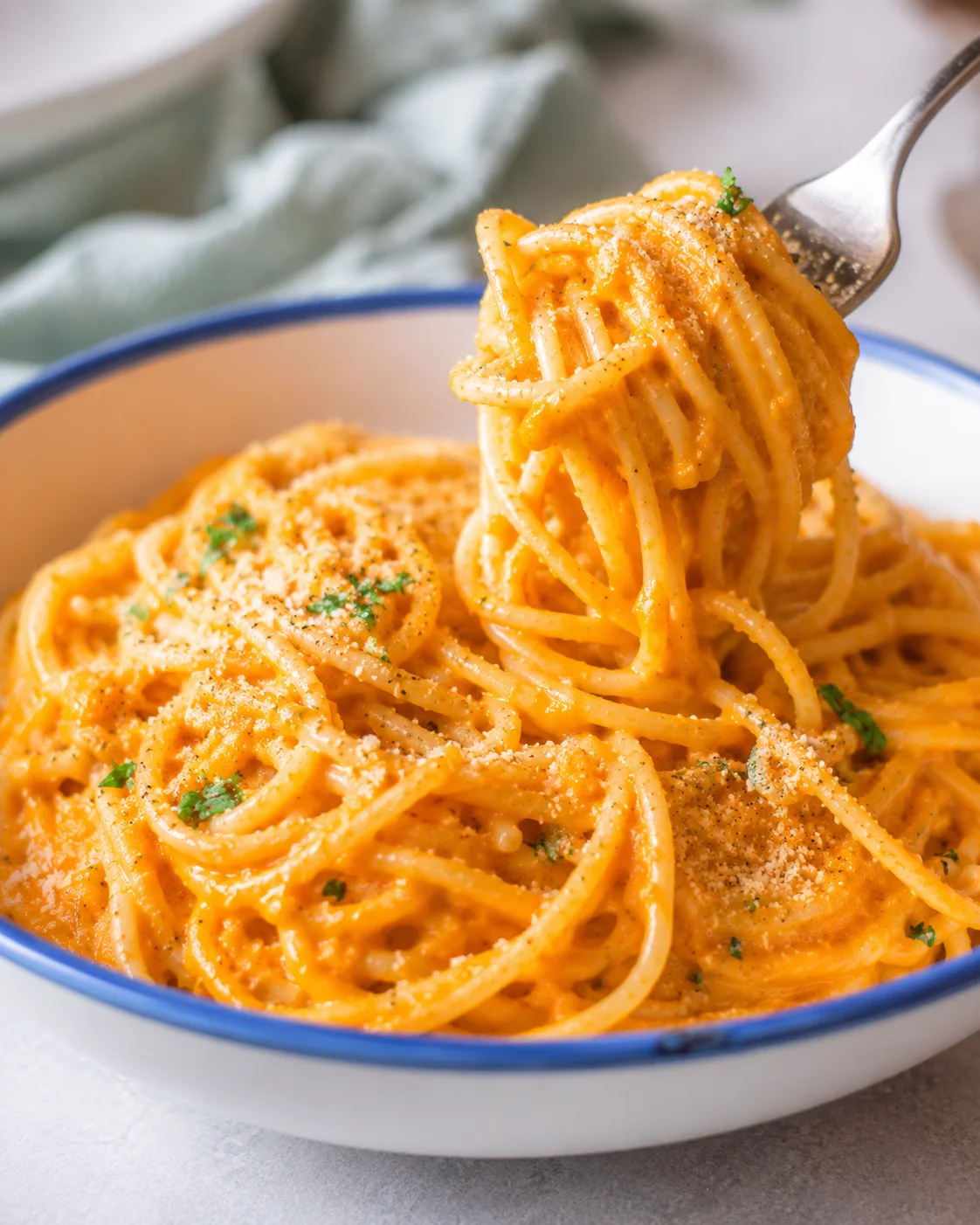 Fork lifting a twirl of vegan pumpkin pasta from a bowl