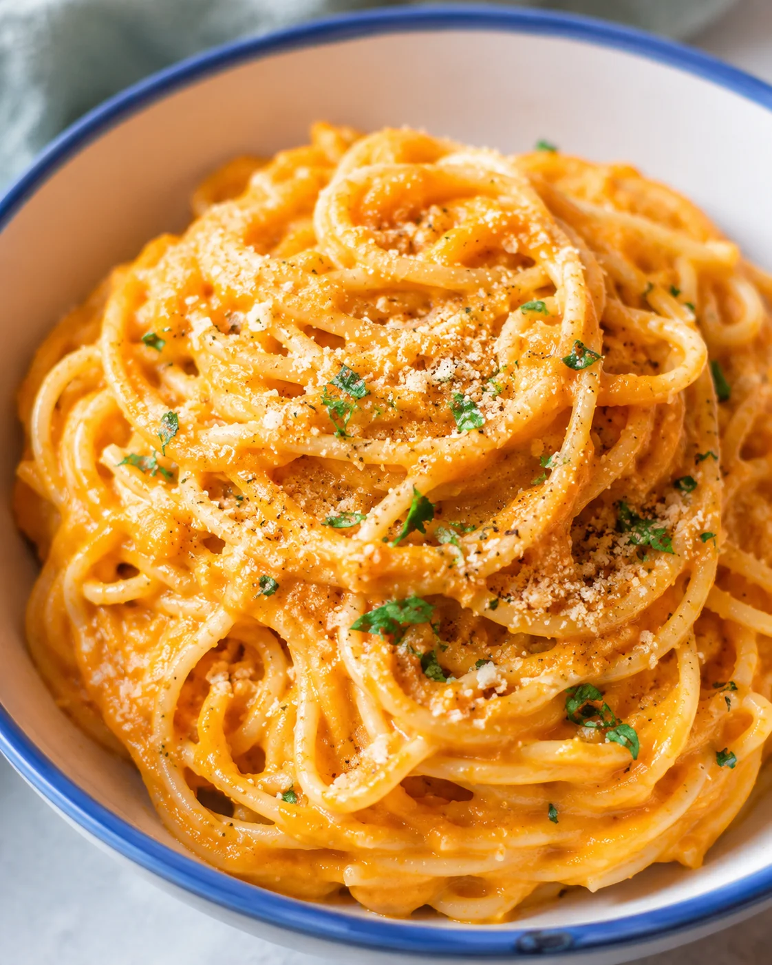Bowl of creamy vegan pumpkin pasta topped with parsley and pepper